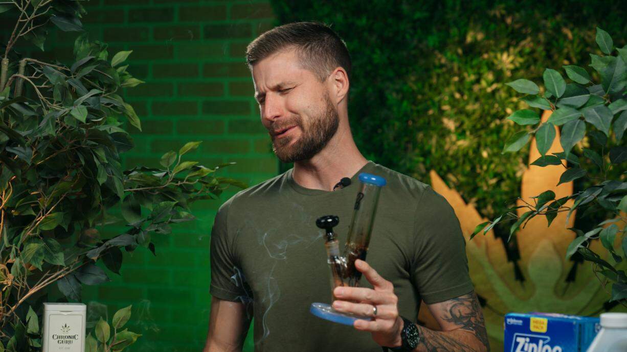 CEO grimaces while holding a dirty bong, a fitting visual for tutorials on how to clean your bong and keep hits smooth.