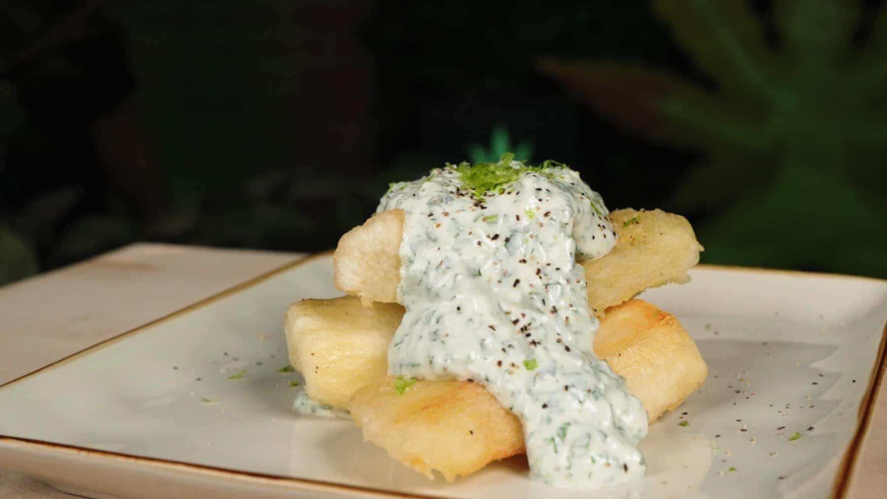 Yuca Fries with Infused Cilantro Garlic Mayo beautifully presented on a white plate