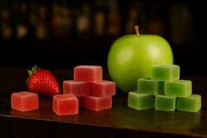 Stack of 10mg strawberry and green apple gummies beside real fruit garnish, ideal for first-time edible consumers easing into cannabis.