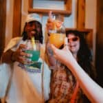 Laughing friends doing 'cheers' with their infused drinks.