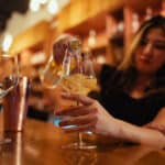 A Chronic Guru budtender pours white wine into a glass.