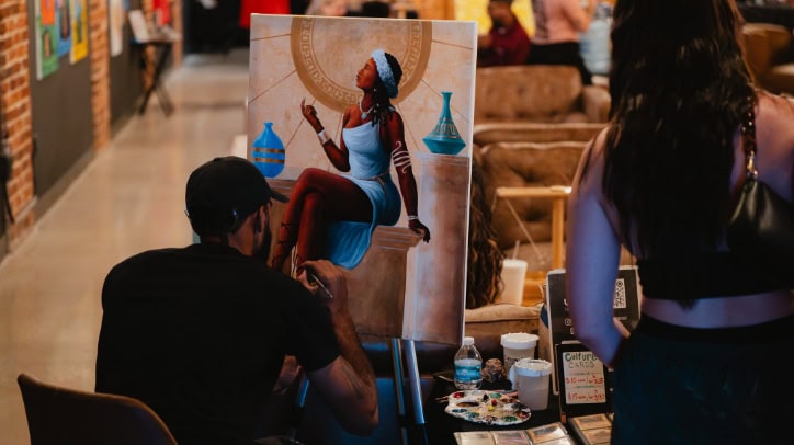 An artist paints a piece inside Chronic Guru lounge during an artist showcase.