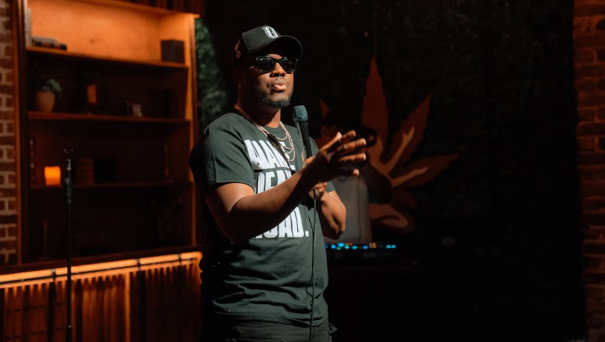 A comedian gestures with his hand while telling a joke at comedy night at Chronic Guru