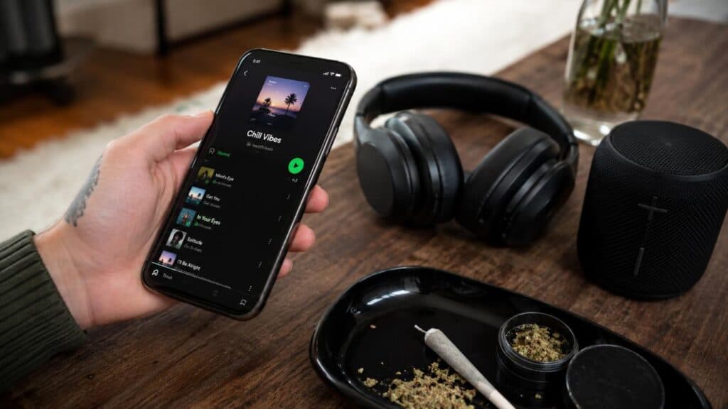 Best music when high selected on a phone beside headphones and cannabis accessories