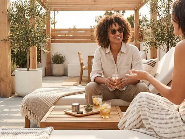 Two adults relaxing on a sunny patio with iced drinks and the best strains for summer